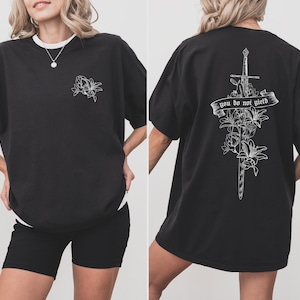 May include: Black oversized t-shirt with a white floral design on the front and a sword with flowers and the text "you do not yield" on the back.