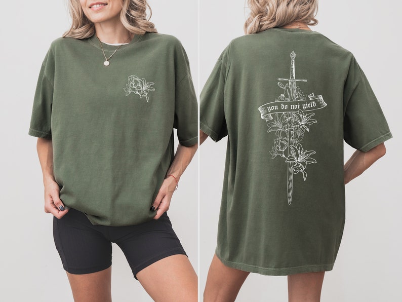 May include: A green t-shirt with a white floral design on the front and a sword with flowers and the text "you do not yield" on the back.