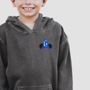 Pu&ograve; includere: Una felpa con cappuccio grigia scura con un cappello da mago di Topolino ricamato in blu e bianco sul davanti.