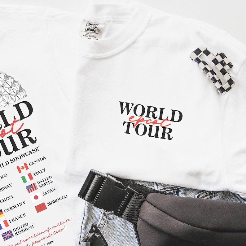 May include: White t-shirt with the text "WORLD EPCOT TOUR" printed in black. The text "EPCOT" is in red. The shirt also features a graphic of the Epcot World Showcase with flags representing different countries.