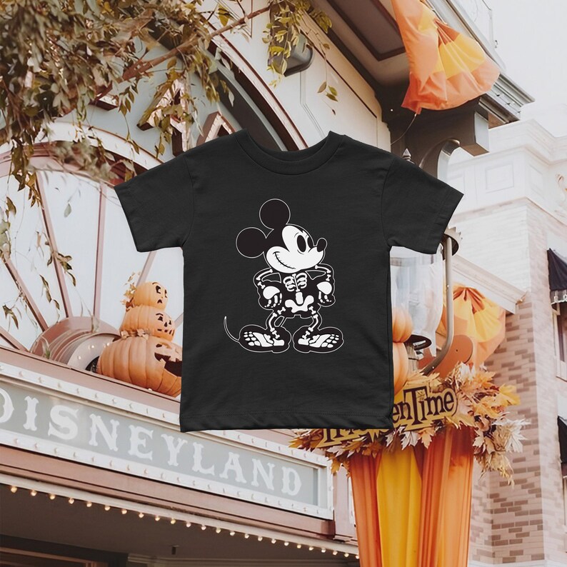 May include: Black t-shirt featuring a white skeleton Mickey Mouse graphic. The shirt is a Halloween themed design.