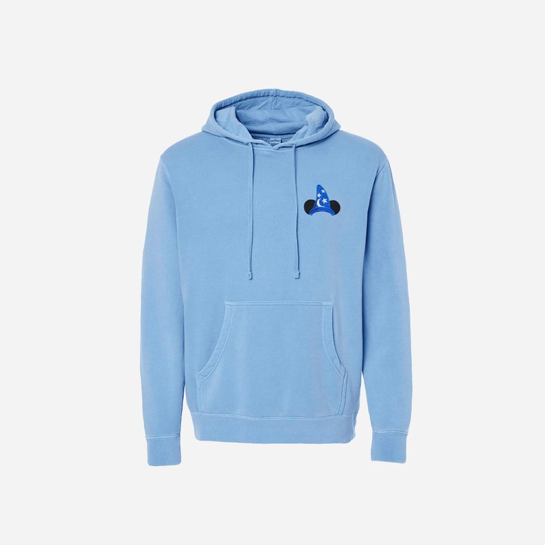 Pu&ograve; includere: Una felpa con cappuccio blu chiaro con una piccola immagine ricamata di Topolino che indossa un cappello da mago sul petto sinistro.
