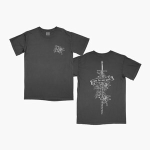 May include: A charcoal grey t-shirt with a white floral design on the front and a sword with flowers and the text "you do not wield" on the back.