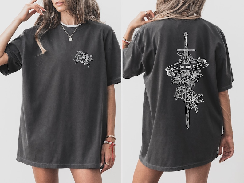 May include: A dark gray oversized t-shirt with a white floral design on the front and a sword with flowers and the text "you do not yield" on the back.