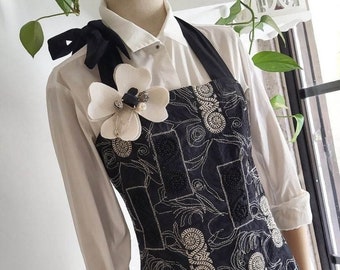 Cleavage dress in black embroidered cotton and flower brooch