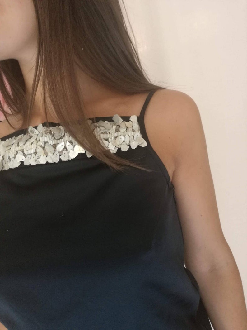 May include: A black sleeveless top with a silver sequined trim across the neckline.