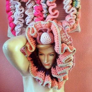 May include: A mannequin wearing a pink, white, and green crocheted hat and a pink, brown, and beige crocheted collar.