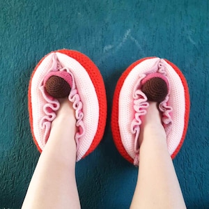 May include: A pair of red and pink crocheted slippers with a brown crocheted ball in the center of each slipper.