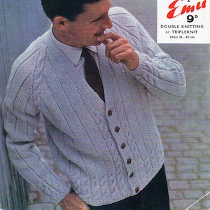 May include: A light blue knitted cardigan with a cable knit pattern and brown buttons. The cardigan is shown on a model and has a V-neck. The text on the label reads "Emu 9° Double Knitting or Tripleknit Chest 34-42 ins."