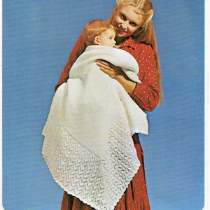 Peut inclure: Une femme en robe rouge tient un bébé enveloppé dans une couverture de bébé en crochet blanc avec une bordure en dentelle.