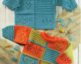May include: Two knitted sweaters with colorful patchwork designs and embroidered details. The sweaters are laid out on a sandy surface with seashells.