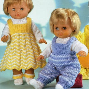 May include: Two dolls wearing knitted outfits. The doll on the left is wearing a yellow and white striped dress with a white cardigan. The doll on the right is wearing blue and white striped dungarees with a white cardigan.