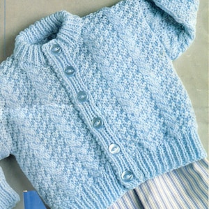 May include: A light blue knitted baby cardigan with a button closure. The cardigan has a cable knit pattern and is 16-22 inches in size.