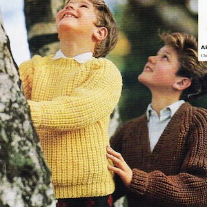 May include: Two children looking upwards, wearing knitted sweaters. One child is wearing a yellow sweater with a white collar and patterned pants. The other child is wearing a brown sweater. The background is a blurred outdoor scene.