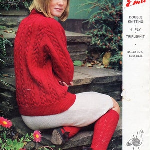 Op de afbeelding: Een rode gebreide trui met een kabelbreipatroon, gedragen met een witte rok en rode kousen. Het model zit op een stenen trede. De afbeelding bevat de tekst "2499 Emu Double Knitting 4 Ply Tripleknit 30-40 inch bust sizes NINEPENCE".