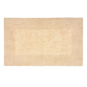 May include: A beige bath mat with a slightly darker border. The mat is made of a soft, absorbent material.