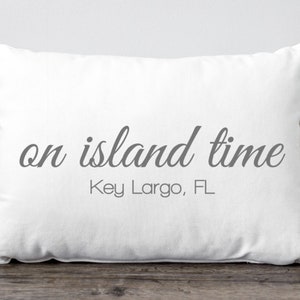 May include: White pillow with the text "on island time" and "Key Largo, FL" in gray lettering.