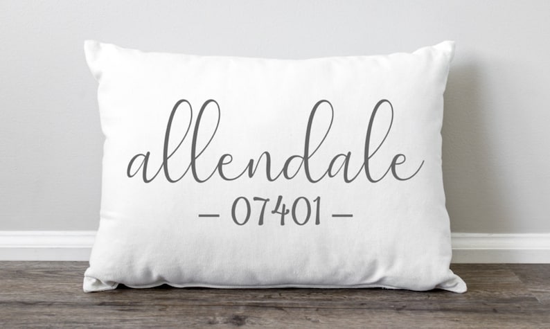 K&ouml;nnte beinhalten: Wei&szlig;es Kissen mit dem Text "allendale - 07401 -" in grauer, kursiv geschriebener Schrift.