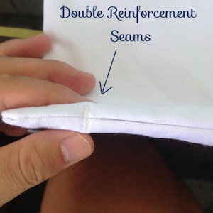 K&ouml;nnte beinhalten: Nahaufnahme einer wei&szlig;en Stoffnaht mit dem Text "Double Reinforcement Seams" dar&uuml;ber.