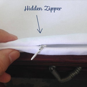 K&ouml;nnte beinhalten: Nahaufnahme eines wei&szlig;en Kissenbezugs mit einem verdeckten Rei&szlig;verschluss. Der Rei&szlig;verschluss ist wei&szlig; und befindet sich an der Naht des Kissenbezugs.