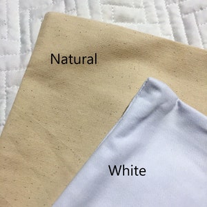 K&ouml;nnte beinhalten: Zwei Stoffmuster, eines in Naturbeige und eines in Wei&szlig;, mit den Worten "Natur" und "Wei&szlig;" bedruckt.