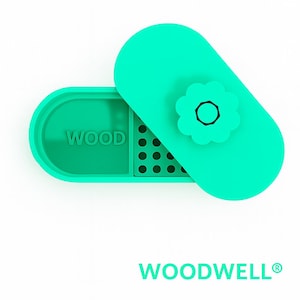 May include: A teal-colored container with a matching lid, featuring a flower-shaped accent. The word "WOOD" is embossed on the container. The brand name "WOODWELL®" is displayed below. The design is minimalist and modern.