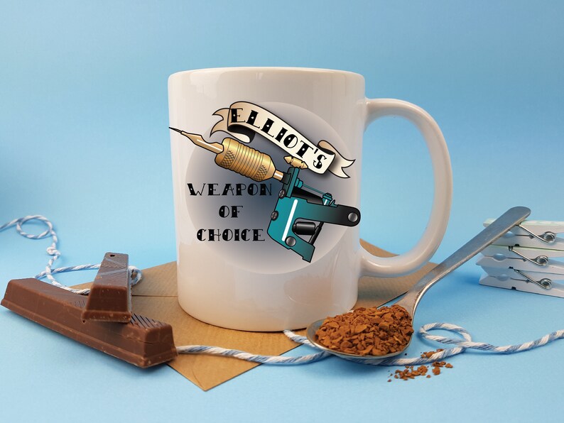May include: White ceramic mug with a tattoo machine design and the text "Elliot's Weapon of Choice".