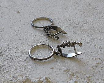 Silverringar dinglar på ett ådrat örhänge med spänne, handgjort i sterlingsilver.