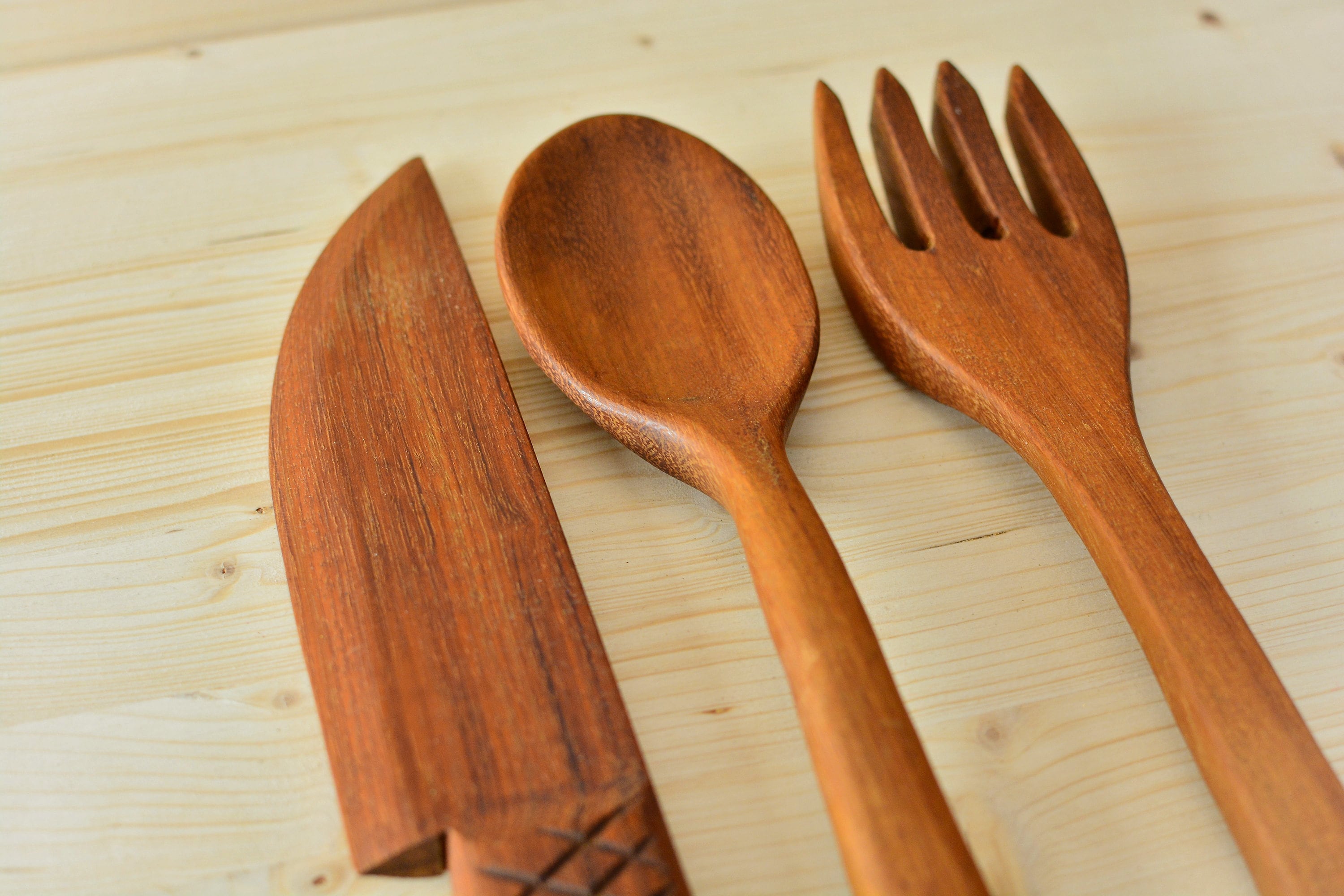 Rustic style wooden kitchen utensil rack with decorative utensils.