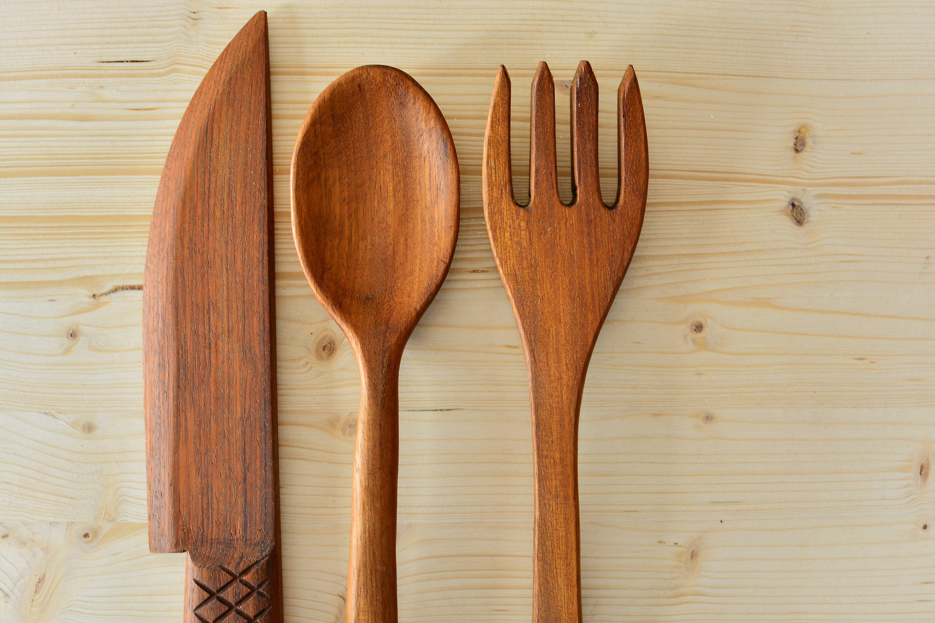 Rustic style wooden kitchen utensil rack with decorative utensils.