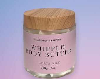 May include: A white jar with a wooden lid filled with whipped body butter. The label reads "CLAUDIAS ESSENCE WHIPPED BODY BUTTER GOATS MILK 200g | 7oz".