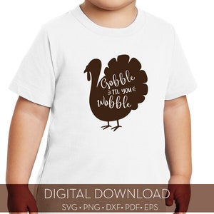 May include: White t-shirt featuring a brown turkey silhouette and the text "Gobble til you wobble".