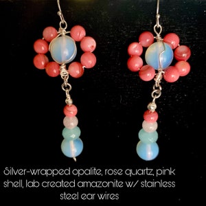 May include: A pair of dangle earrings with silver-wrapped opalite, rose quartz, and pink shell beads. The earrings are suspended from stainless steel ear wires.