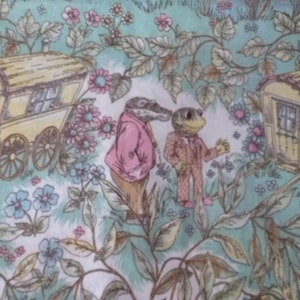 May include: A whimsical fabric design featuring two animal characters, a frog and a crocodile, standing in a field of flowers. The characters are dressed in clothing and are near two small, yellow wagons. The background is a green and white floral pattern.