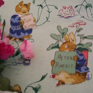 Pode incluir: Um tecido verde com um padrão repetido de Peter Rabbit e Tom Kitten. Peter Rabbit está segurando uma placa que diz "Peter Rabbit" e Tom Kitten está segurando uma placa que diz "Tom Kitten".