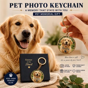 K&ouml;nnte beinhalten: Ein runder Schl&uuml;sselanh&auml;nger aus goldfarbenem Metall mit einem individuellen Foto eines Golden Retrievers, dem Namen Buddy und einem Pfotenabdruck-Symbol auf der Oberfl&auml;che. Der Anh&auml;nger hat einen goldenen Ring und eine schwarze Geschenkbox.