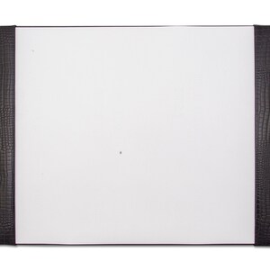 May include: A white desk pad with black faux leather edges. The edges have a crocodile skin pattern.