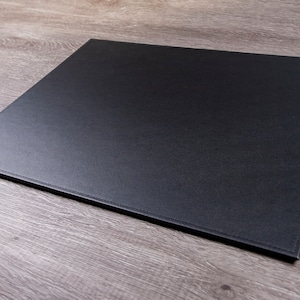 May include: A black leather desk mat with stitched edges.