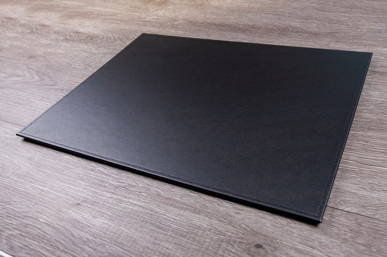 May include: A black leather desk mat with stitched edges.