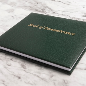 May include: A dark green leather-bound book with the words "Book of Remembrance" embossed in gold on the front cover.