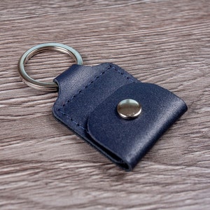 May include: A dark blue leather key chain with a silver ring and a silver button closure.