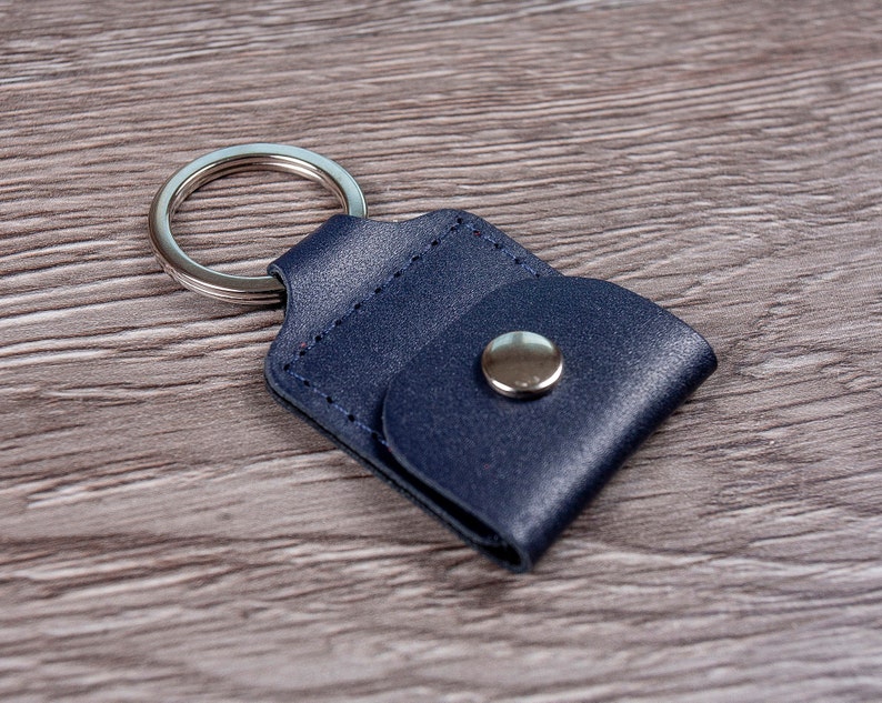 May include: A dark blue leather key chain with a silver ring and a silver button closure.