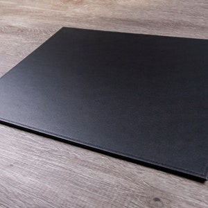 May include: A black leather desk mat with stitched edges.