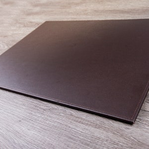 May include: A brown leather desk mat with stitched edges.