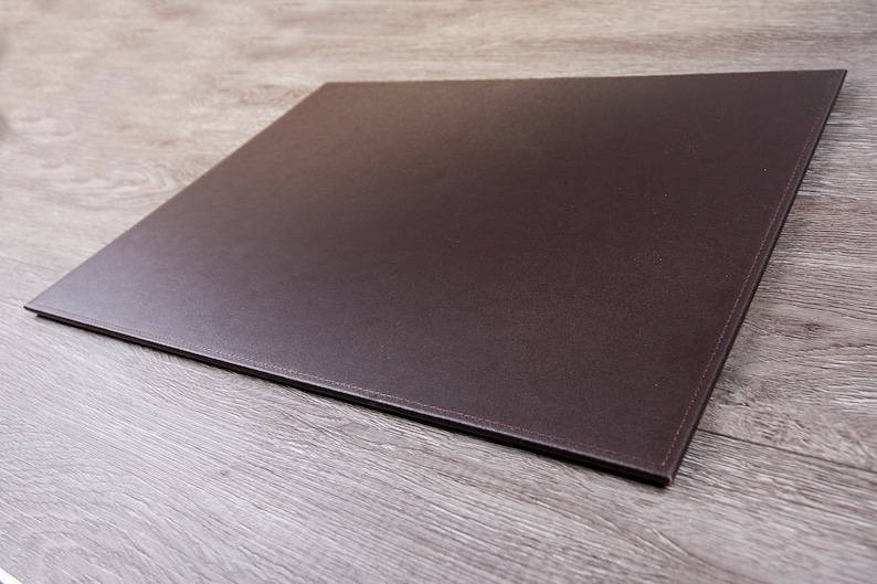 May include: A brown leather desk mat with stitched edges.