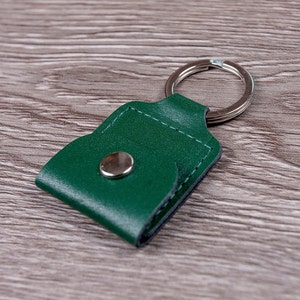 May include: A green leather keychain with a metal ring and a snap closure.