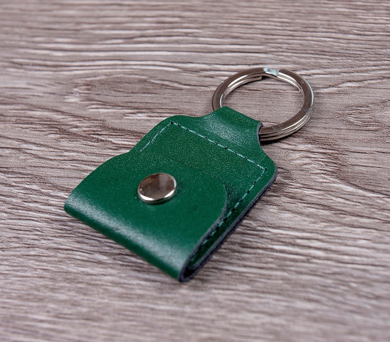 May include: A green leather keychain with a metal ring and a snap closure.