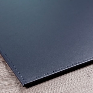 May include: A dark blue leather desk mat with stitched edges.