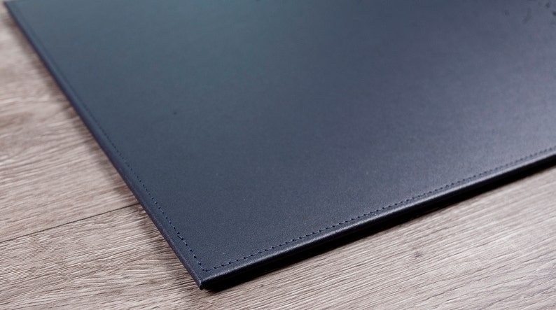 May include: A dark blue leather desk mat with stitched edges.