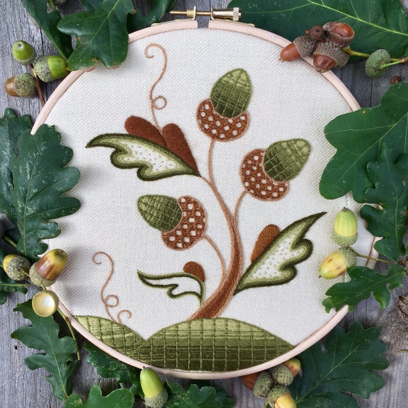 May include: Embroidered hoop art featuring a stylized green and brown acorn tree with leaves on a white background.